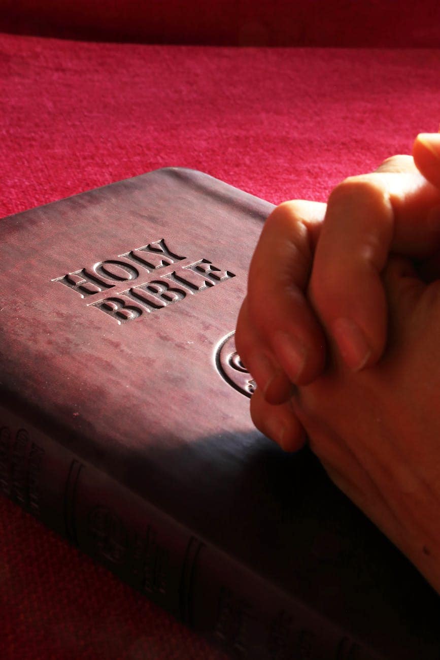 person hands on holy bible